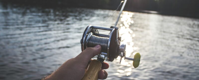 person holding black and silver fishing reel